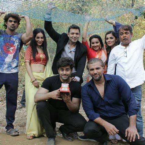 a group of people posing for a photo in front of some netted trees and bushes