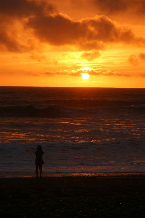 A person standing on a beach at sunset photo – Free Beach Image on Unsplash