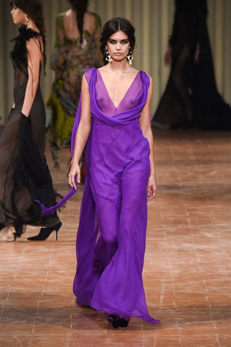 a model walks down the runway in a purple gown