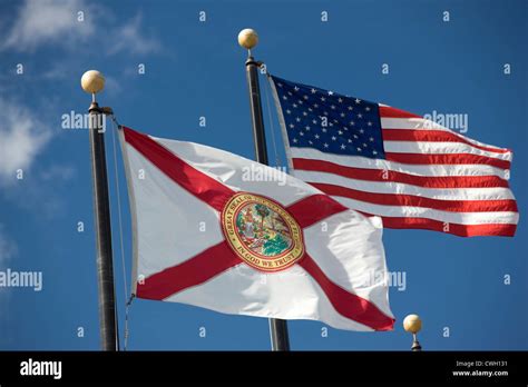 FLORIDA STATE FLAG UNITED STATES FLAG FLYING ON FLAGPOLES ON BLUE SKY ...