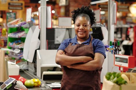 Happy Young Shop Assistant in Uniform Keeping Her Arms Crossed by Chest ...