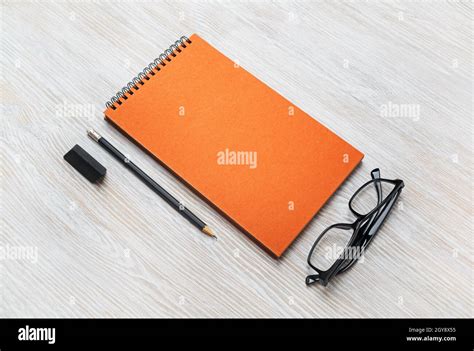 Black notepad, glasses, pencil and eraser on light wood table ...