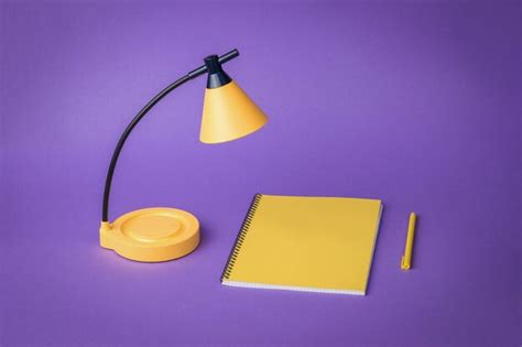 Premium Photo | Minimal concept yellow desk lamp yellow notebook and pen on a purple background ...