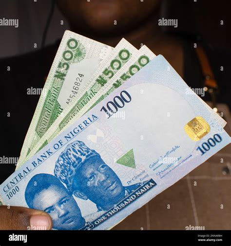 Hand holding the new Nigerian 1000 and 500 Naira notes on a white ...