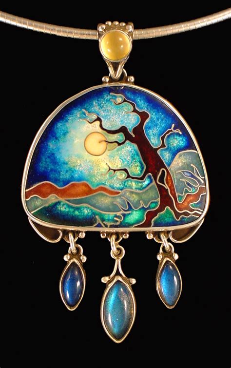 a necklace with an image of a tree and two tears hanging from the front