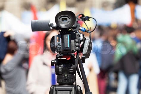 Filming female reporter with a video camera, blurred crowd in the ...