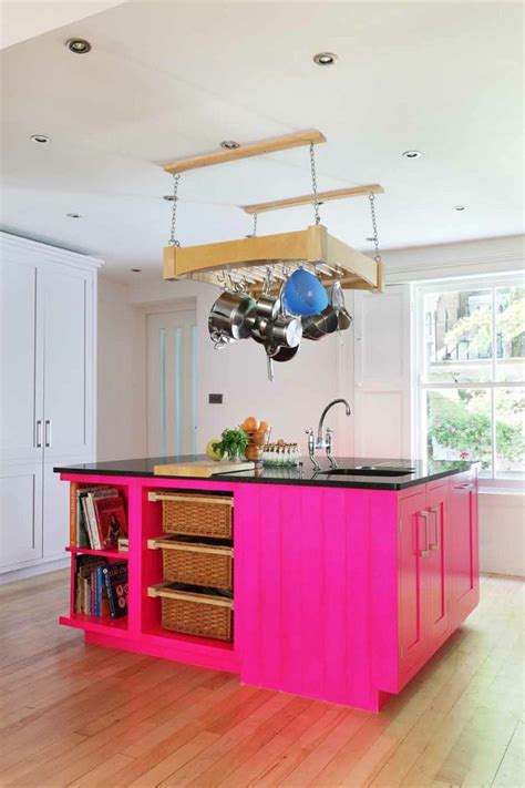 a kitchen with pink island in the middle of it and hanging pots on the rack