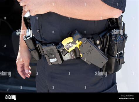 Police officer's duty belt includes a yellow Taser "stun gun" in a holster Stock Photo - Alamy