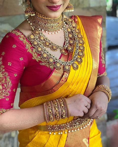 a woman in a yellow and red sari with gold jewelry on her neck,