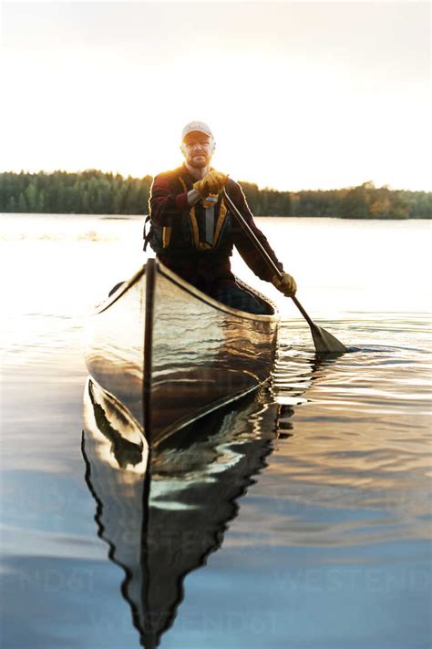 Man paddling canoe on lake stock photo