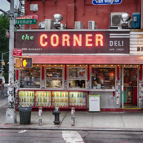 a corner deli with neon signs on the side of it's storefront