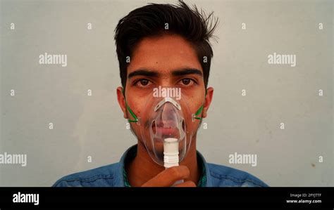 Young Man wearing oxygen mask at the home alone. A Coronavirus infected person difficulty in ...