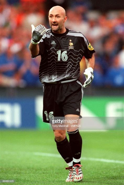 a soccer player with his hand up in the air and smiling at the camera while standing on