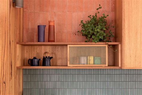 a shelf filled with pots and vases on top of a tiled wall