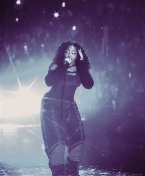 a woman standing on top of a stage in front of a crowd holding a microphone