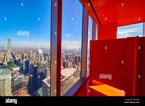 Surreal orange bathroom stall with windows overlooking New York City skyline high up Stock Photo ...