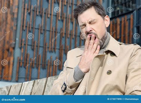 Sleepy Man Yawning on Wooden Bench Outdoors. Space for Text Stock Photo ...