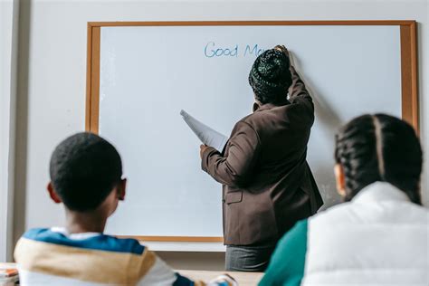 Black teacher writing on whiteboard for diverse pupils · Free Stock Photo