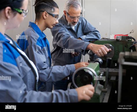 Instructor giving lathe machine training to trainees at workshop Stock ...