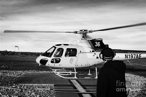 crew member watches papillon helicopter tour full of passengers take off from helipad at Grand ...