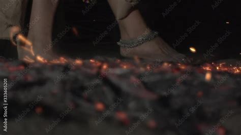 Woman with bare feet resolutely walks over hot coals. Brave woman with bare feet runs over red ...