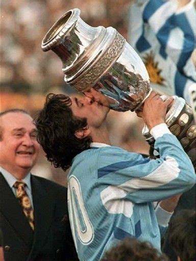 two men kissing each other while holding up a trophy in front of their faces and people watching