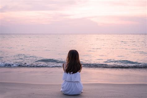 Premium Photo | Lonely young asian woman sitting on the beach at sunset