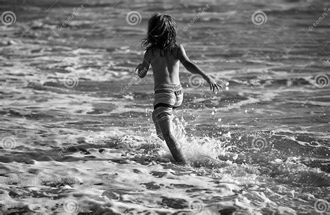 Back View of Kid Boy Have Fun on Tropical Sea Beach. Funny Child Run with Splashes by Water Pool ...