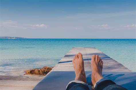 Los pies del hombre descansando en la playa junto al mar en verano ...