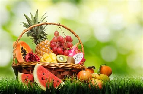 Basket of fresh tropical fruits on green grass and on nature bac ...