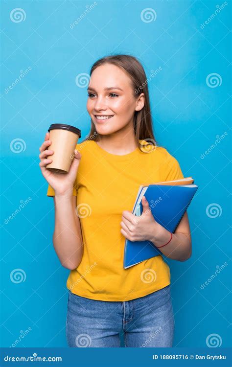 Young Woman Smiles and Holds Books and a Glass of Coffee or Tea in Her ...