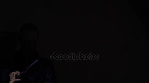 Man pulling out his gun in the darkness and aiming at the camera. 4k ...