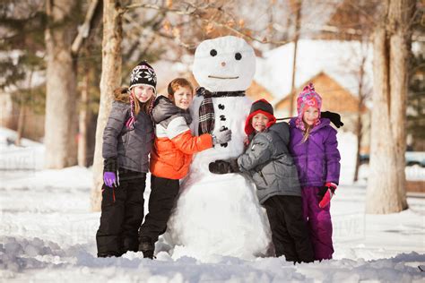 Caucasian family building snowman in snow - Stock Photo - Dissolve