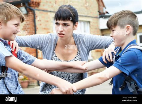 Teacher Stopping Two Boys Fighting In Playground Stock Photo - Alamy