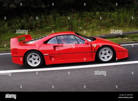 Red modern classic Ferrari F40 in profile (side view) driving on the public road Stock Photo - Alamy