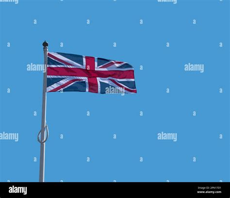 Closeup illustration of a Union Jack flag seen in strong winds at the top of a flag pole Stock ...