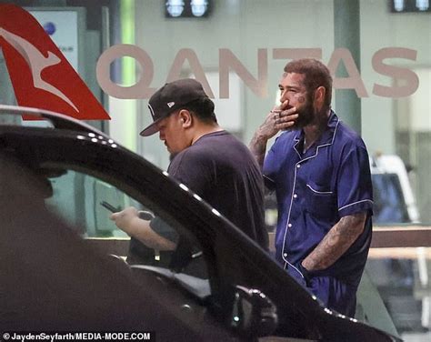 Post Malone smokes a cigarette in expensive silk pyjamas as he touches down in Sydney with his ...