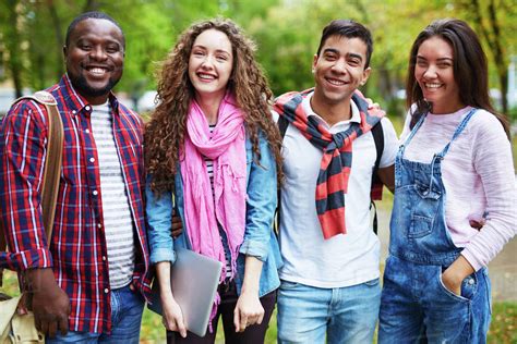 Portrait of happy college students standing together outdoors - Stock Photo - Dissolve