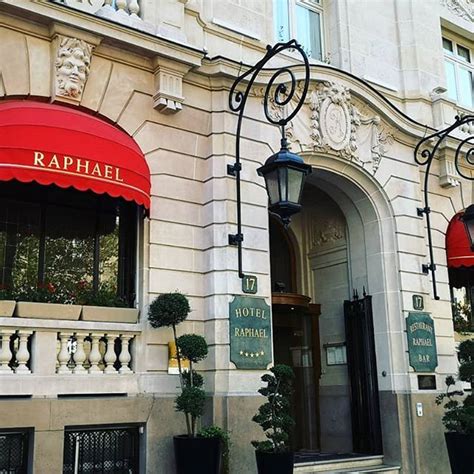 the entrance to a building with red awnings and black planters in front