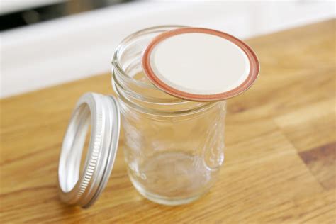 a glass jar sitting on top of a wooden table next to a metal container with a lid