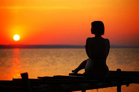 Silhouette of Woman Sitting on Dock during Sunset · Free Stock Photo