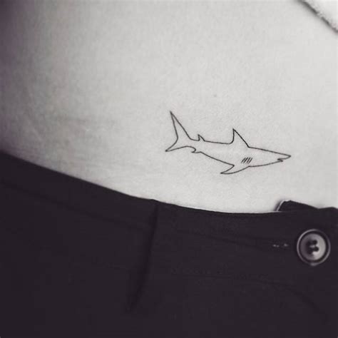 Minimalist shark tattoo on the pelvis.