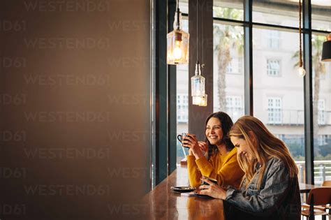 Two female friends laughing and having fun at a cafe. Two women ...