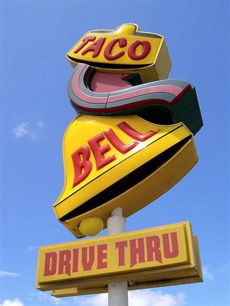 the sign for taco bell drive thru is in front of a blue sky with clouds