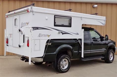 a truck with a camper attached to it's bed parked in front of a building