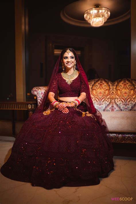 Photo of Bride dressed in a deep maroon bridal lehenga.