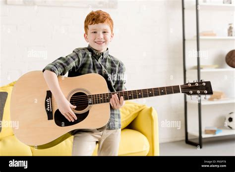 cute little boy holding acoustic guitar and smiling at camera Stock ...