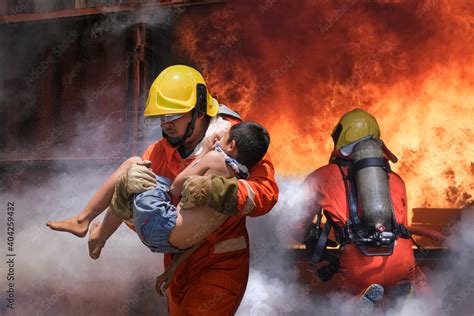 Firefighter holding child boy to save him in fire and smoke,Firemen rescue the boys from fire ...