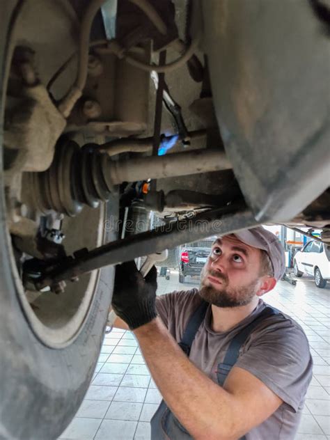 A Mechanic in a Car Repair Shop Repairs the Suspension of a Car on a Lift. a Professional ...