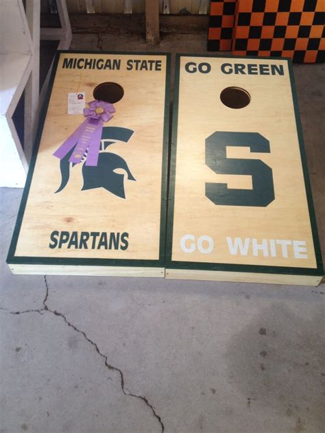 two cornhole boards with michigan state logos on them